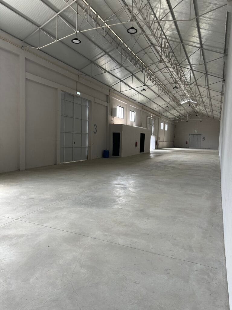 Nave do armazém da Show Reel com portão de acesso e piso em betão, em Lisboa