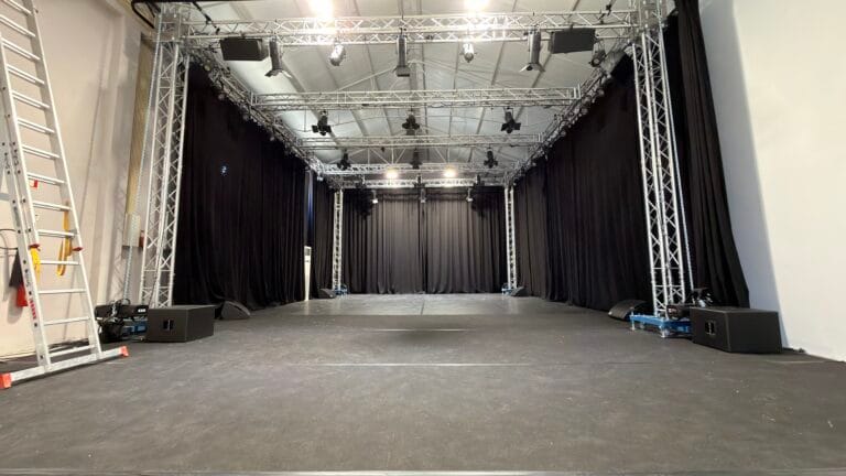 Set montado no armazém da Show Reel com trussing, iluminação e cortinas negras, em Lisboa